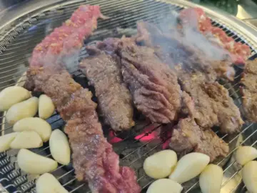 이가네명인갈비살 부산시청점에서 숯불 위에서 구워지는 갈비살과 마늘