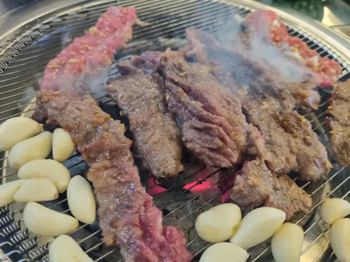 이가네명인갈비살 부산시청점에서 숯불 위에서 구워지는 갈비살과 마늘