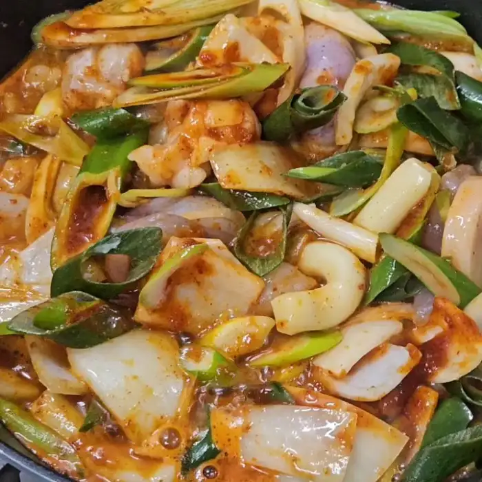 조리 중인 낙곱새의 모습, 매콤한 양념과 함께 다양한 채소와 해산물, 대창이 어우러져 있습니다.