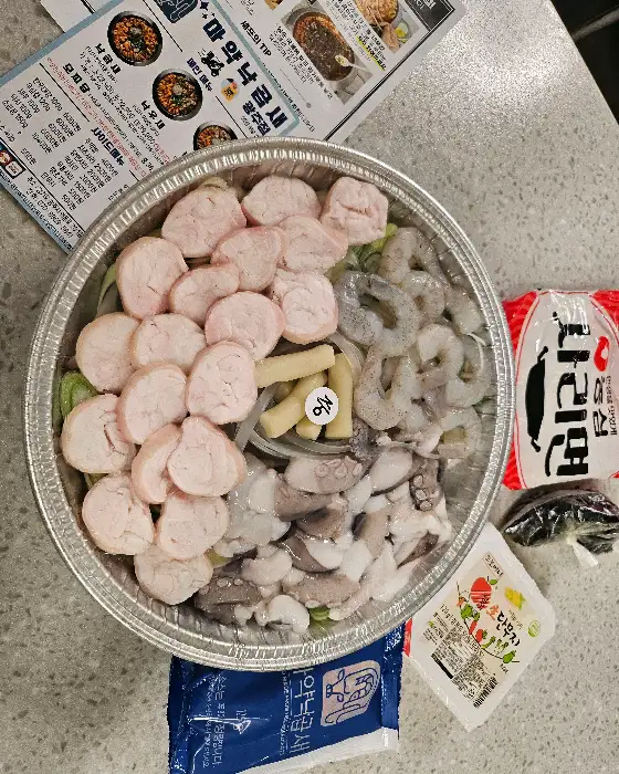 포장용기 안에 푸짐하게 담긴 낙곱새 재료들, 다양한 종류의 해산물과 곱창, 채소가 보기 좋게 담겨 있습니다.