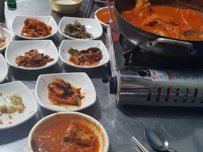 나연식당 테이블에 놓인 여러 가지 밑반찬과 닭볶음탕 냄비