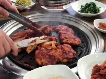 옥선가숯불닭갈비막국수에서 숯불에 구워지는 닭갈비와 밑반찬 모습