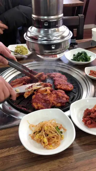 옥선가숯불닭갈비막국수에서 숯불에 구워지는 닭갈비와 밑반찬 모습