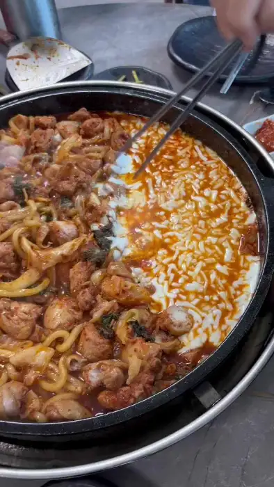 두 사람이 젓가락으로 닭갈비와 치즈를 집고 있는 모습