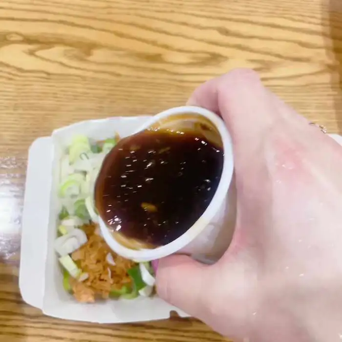 손이 소스를 소스 종지에 따라 붓는 모습. 소스는 갈색빛을 띤다.