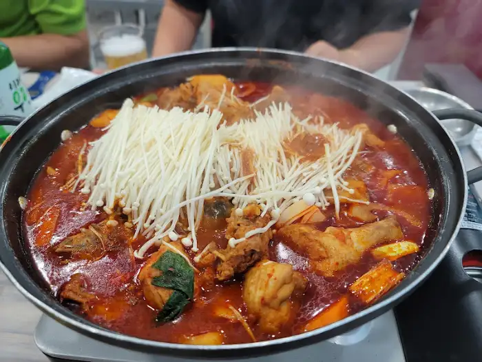 넓은 냄비에 담긴 닭볶음탕에 팽이버섯이 가득 올라가 끓고 있는 모습