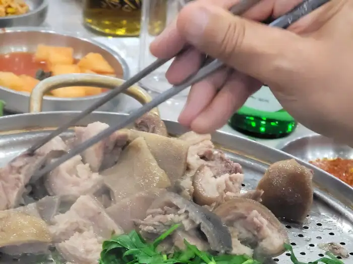 젓가락으로 족발 부위를 집어 올리는 손의 모습