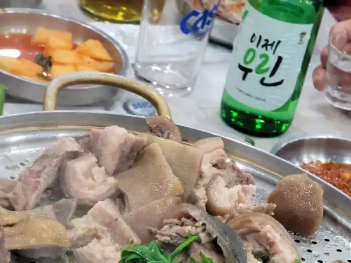 테이블 위에 놓인 족발 접시와 소주병, 맥주잔이 보인다.