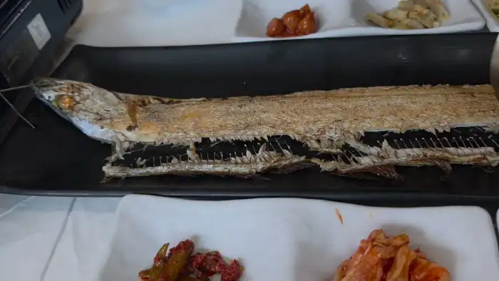 검은색 접시에 놓인 통갈치구이의 윗부분이 클로즈업 되어 있습니다.