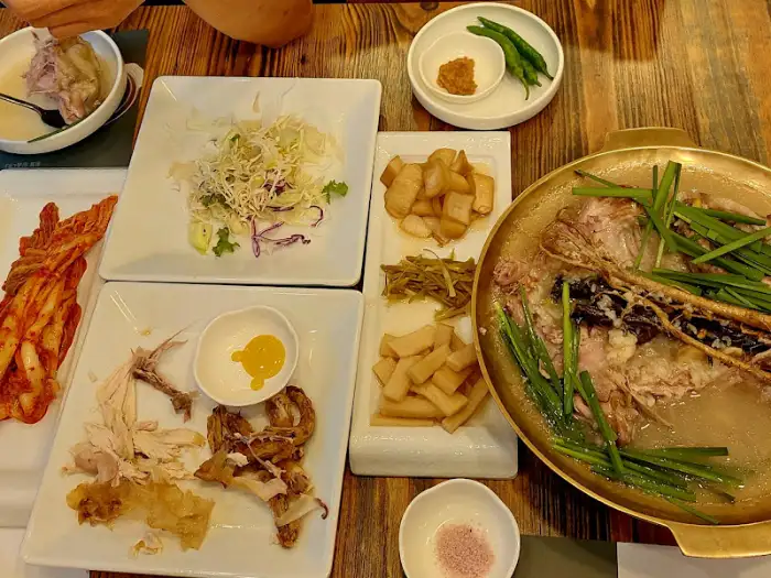 산골애의 푸짐한 한상차림, 다양한 반찬과 함께 오리백숙을 즐기는 모습