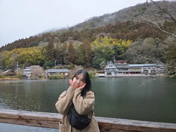 경치 좋은 호숫가를 배경으로 포즈를 취하고 있는 여성.