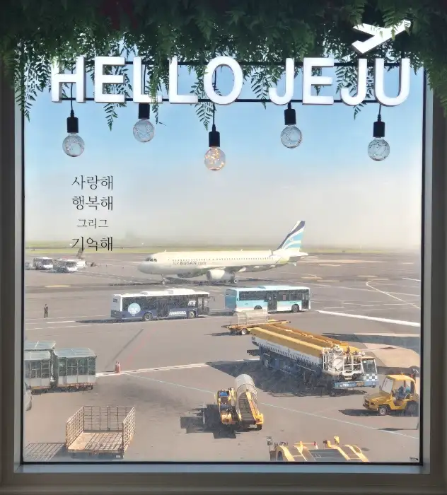 창밖으로 보이는 제주공항 풍경과 HELLO JEJU 간판