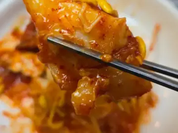 젓가락으로 집어 올린 먹음직스러운 금복이네찜 아구찜 한 점