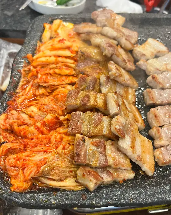 노릇하게 익은 삼겹살과 곁들여 먹기 좋은 김치의 모습