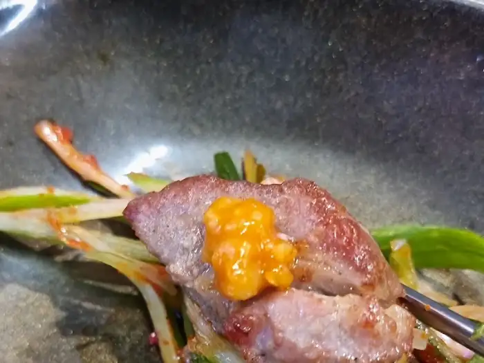 식껍 서대문역 직영점에서 고기에 노란 소스를 얹어 먹는 모습
