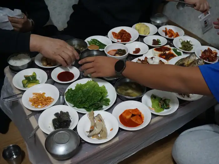 테이블 가득 차려진 남도 백반 반찬들과 밥, 그리고 사람들이 식사하고 있는 모습.
