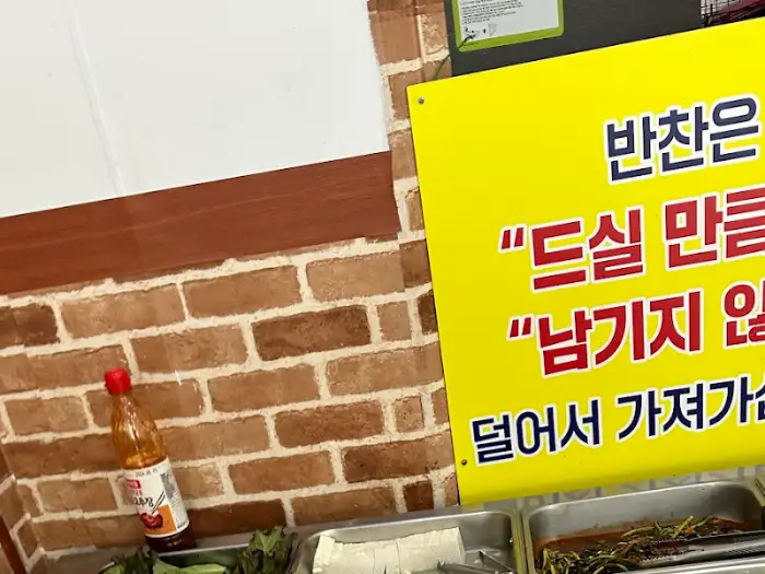 노란색 안내판에 '반찬은 드실 만큼만 남기지 않고 가져가세요'라고 적혀 있음