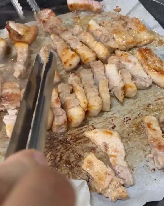 노릇하게 구워지고 있는 삼겹살과 곁들임 메뉴