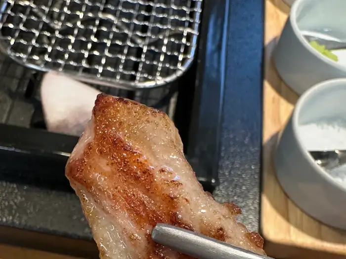 집게로 집어 올린 먹음직스러운 고기 한 점