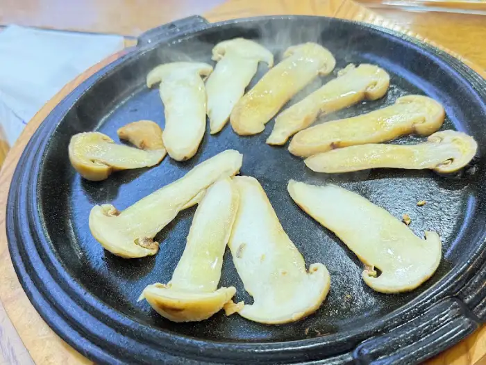 팬 위에서 노릇하게 구워지고 있는 송이버섯의 모습