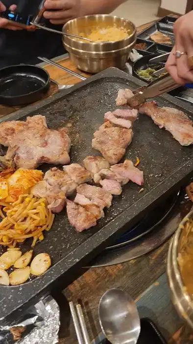 철판 위에서 익어가는 삼겹살과 곁들임 채소