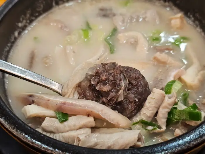 숟가락으로 순대국 속의 순대와 고기를 건져 올린 모습, 푸짐한 건더기가 돋보입니다.