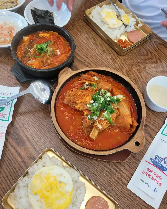 식탁 위에 차려진 다양한 김치찜, 갈비찜, 도시락 메뉴