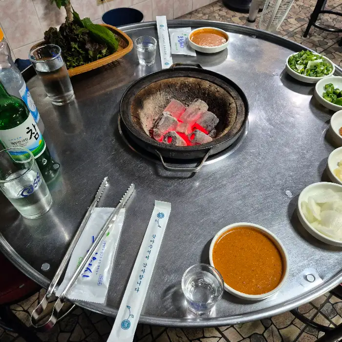 테이블 위에 놓인 숯불 화로와 막창을 곁들일 반찬들