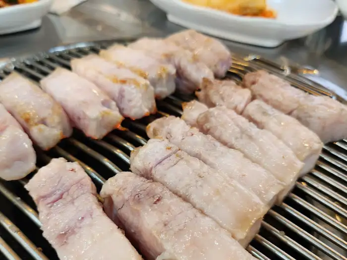 그릴 위에서 구워지고 있는 두툼한 돼지고기 덩어리