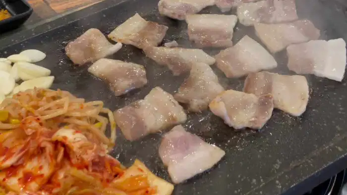 철판 위에서 노릇하게 익어가는 오겹살 조각들