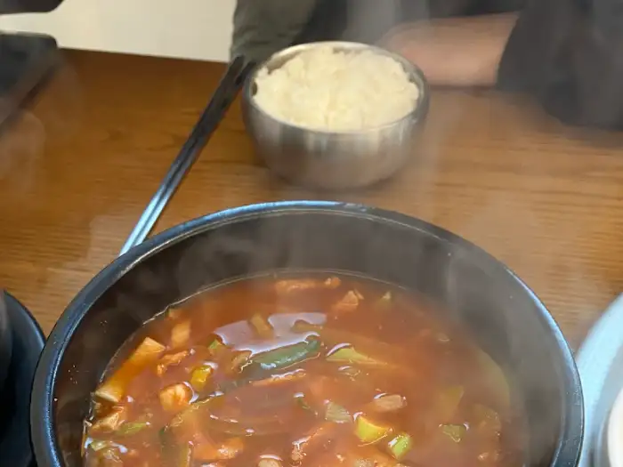 뜨겁게 끓고 있는 김치찌개와 밥이 담긴 공기
