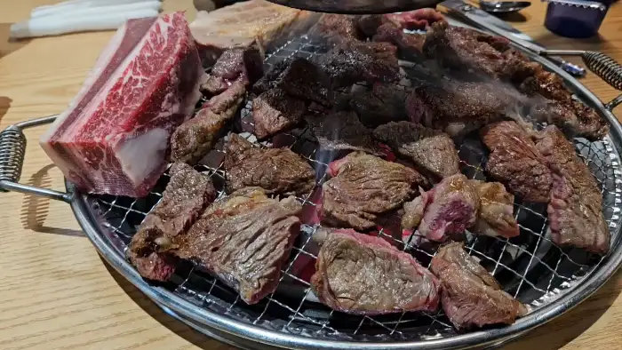 넓은 불판 위에 여러 가지 고기와 뼈가 함께 올라가 있는 모습