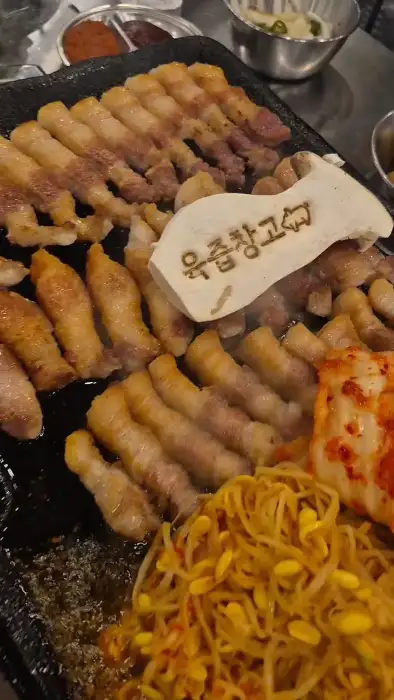 노릇하게 구워지는 삼겹살과 곁들임 메뉴가 푸짐하게 차려진 모습