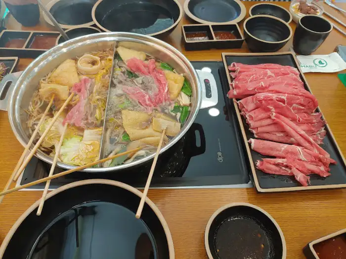 테이블 위에 차려진 두 가지 육수의 샤브샤브와 신선한 고기